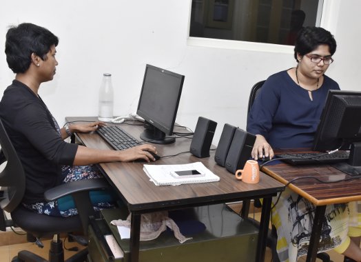 Two people sitting at a table with computers.
