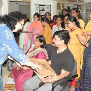Ms. Madhu Singhal and Mr. Satender Singh receive a gift, surrounded by a group of people