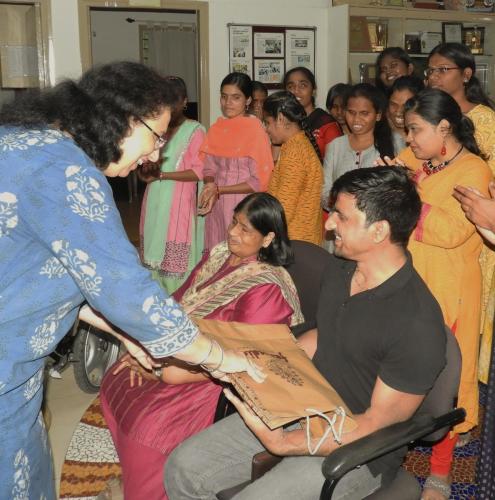 Ms. Madhu Singhal and Mr. Satender Singh receive a gift, surrounded by a group of people.