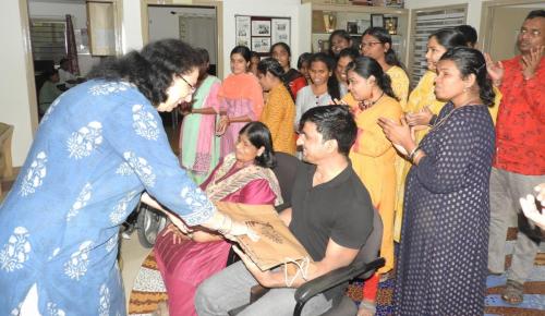 Ms. Madhu Singhal and Mr. Satender Singh receive a gift, surrounded by a group of people.